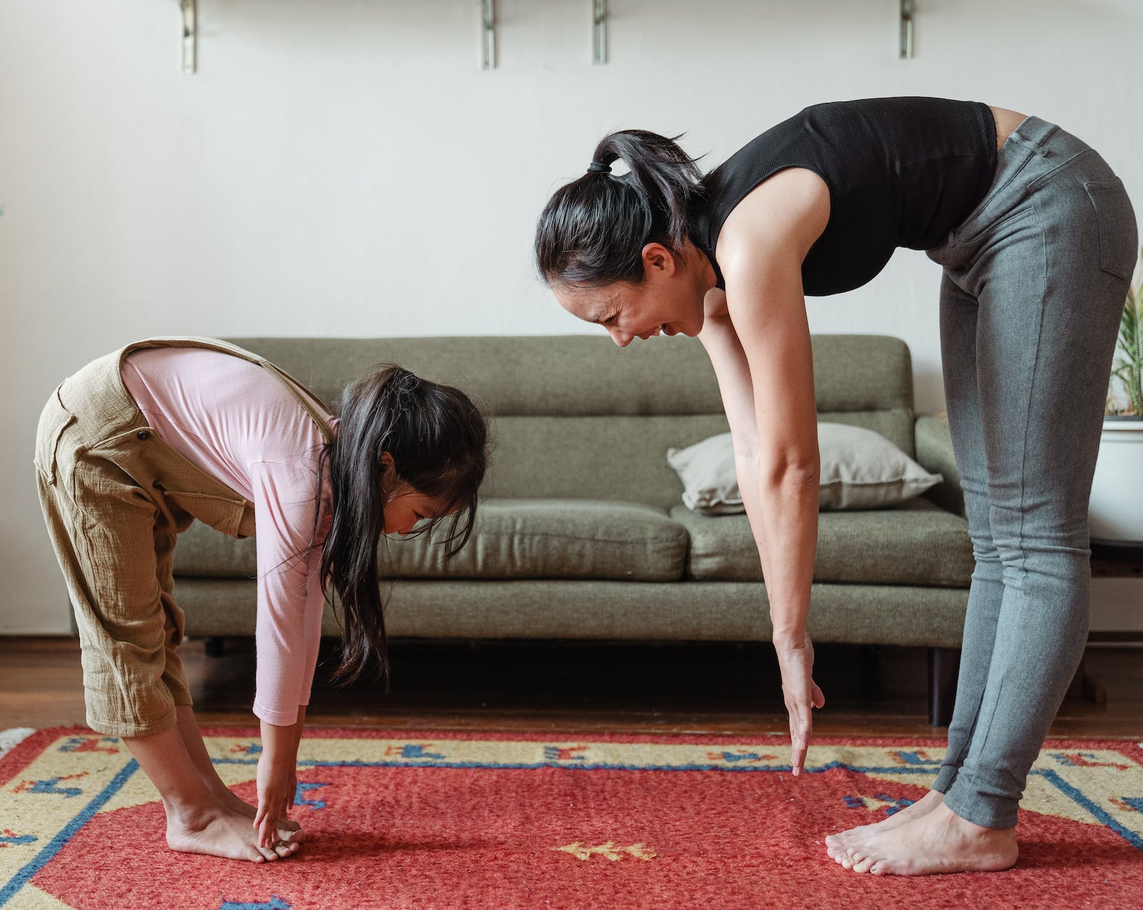 Little girl and woman reaching for thier toes while standing on the living room floor.
Photo by Ketut Subiyanto on Pexels.com